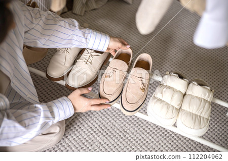Modern woman choosing shoes putting on rack wardrobe comfortable storage organizing top view 112204962