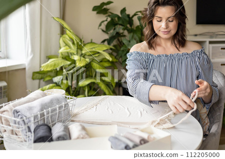 Smiling plus size woman folding linen nightdress in PVC container metal basket storage organizing 112205000