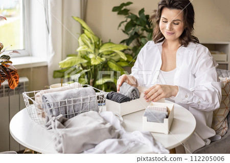 Housewife woman hands folded cotton linen domestic textile in box container and basket on table desk 112205006