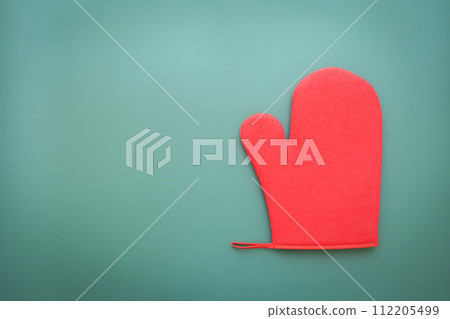 red wool winter glove on green background, christmas decoration red wool winter glove on green background, christmas decoration 112205499