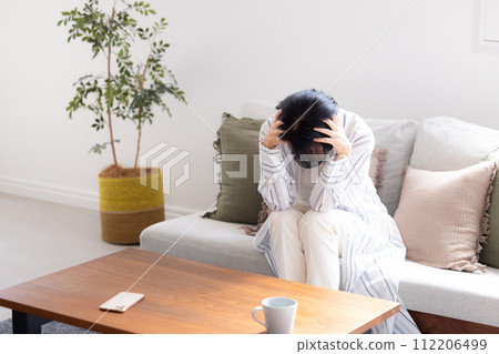 Unwell, middle-aged woman holding back her aching head due to headache 112206499