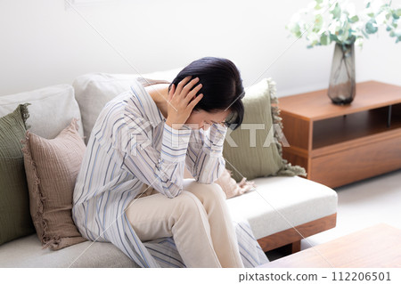 身體不適的中年婦女因頭痛而摀住疼痛的頭 身體不適的中年婦女因頭痛而摀住疼痛的頭 112206501