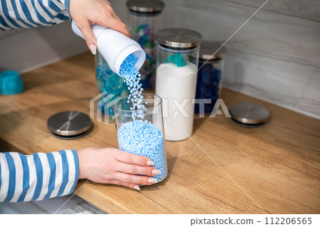 Female housewife hands sprinkle dry blue granular laundry conditioner glass can storage organizing Female housewife hands sprinkle dry blue granular laundry conditioner glass can storage organizing 112206565