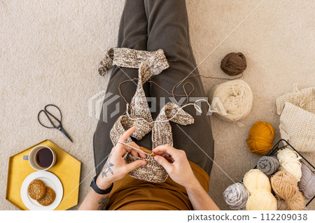 Feminine male hands crochet handmade artwork hobby wooden table with sewing tools closeup top view 112209038