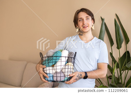 A man holds a large basket with colorful yarn. 112209061