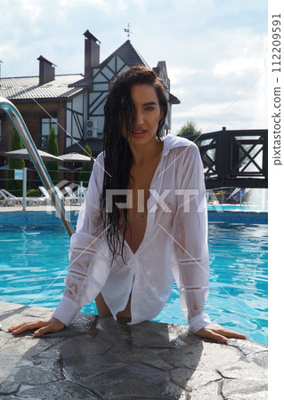 beautiful young sexy woman with vitiligo disease swimming in wet white dress in turquoise water of spa pool, copy space beautiful young sexy woman with vitiligo disease swimming in wet white dress in turquoise water of spa pool, copy space 112209591