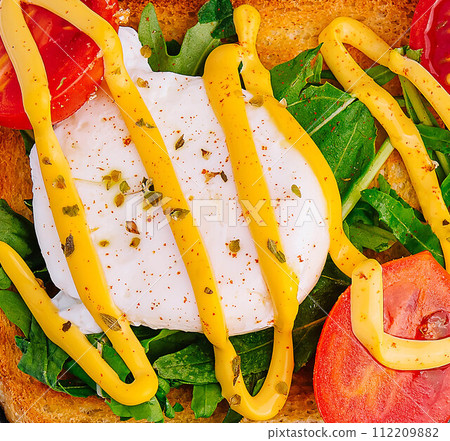 Poached egg with arugula, cherry tomatoes and toast Poached egg with arugula, cherry tomatoes and toast 112209882