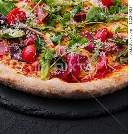 Italian pizza with prosciutto, arugula and cherry tomatoes 112209884