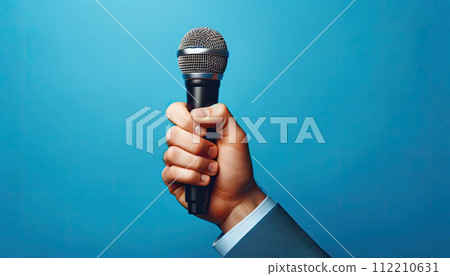 hand firmly holding a microphone on blue background 112210631