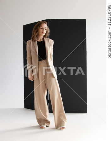 Young brunette curly woman in beige suit. Elegant 112210798