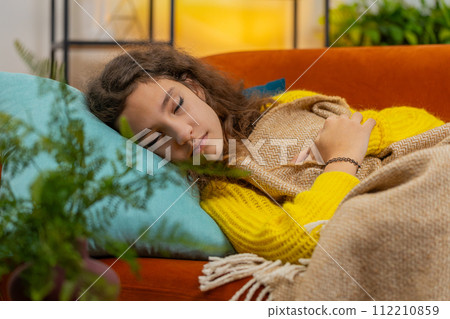 Tired teenager child girl kid lying down in bed taking a rest at home napping falling asleep on sofa 112210859