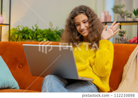 Teen child girl looking at laptop camera, making video webcam conference call with friends family 112210898