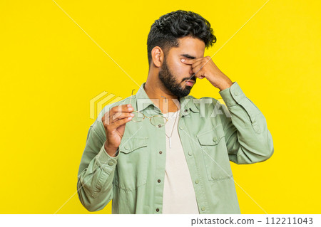 Exhausted tired Indian man takes off glasses, rubbing eyes feels pain, sleepy exhausted, overwork 112211043
