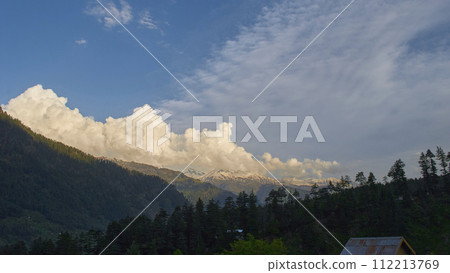 A vast landscape with clear skies, clouds, and snowy mountains. 112213769