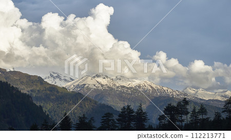 A vast landscape with clear skies, clouds, and snowy mountains. 112213771