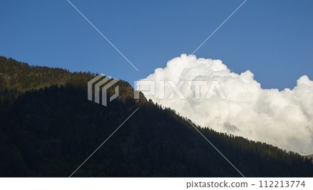 A vast landscape with clear skies, clouds, and snowy mountains. 112213774