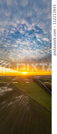 Vertical Portrait of Sunset over Farmlands with Clouded Sky 112213933