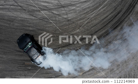 Aerial top view car drifting diffusion race drift car with lots of smoke from burning tires on speed track, Professional driver drifting car with lots of white smoke . Aerial top view car drifting diffusion race drift car with lots of smoke from burning tires on speed track, Professional driver drifting car with lots of white smoke . 112214969