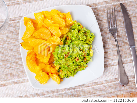 Beer snacks are laid out on plate - chips and portion of thick pasta sauce guacamole 112215369