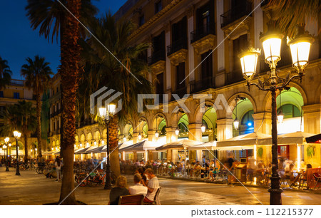 Evening view of bustling Placa Reial in Barcelona with cafes 112215377