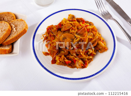 Stewed cabbage is cooked with pieces of mushrooms champignon, carrots, tomato sauce. 112215416