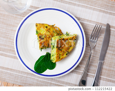 Few small pieces of fluffy egg and spinach omelet are on plate decorated with edible green 112215422