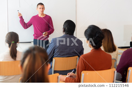 Teacher at university in front of chalkboard with multinational students Teacher at university in front of chalkboard with multinational students 112215546