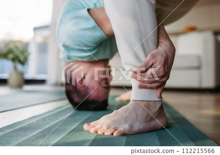 Young man with Down syndrome exercising at home, stretching his body. Workout routine for disabled man. Young man with Down syndrome exercising at home, stretching his body. Workout routine for disabled man. 112215566