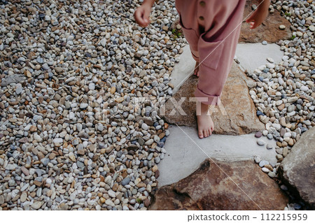 Close up of little girl walking barefoot near the forest cotage,weekend time during summer day. 112215959