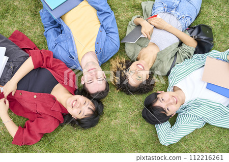 Multinational people lying on the lawn and looking up at the sky 112216261
