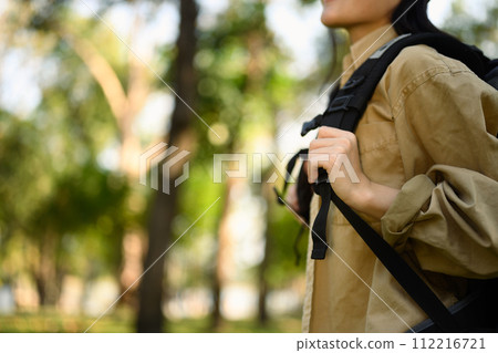 Cropped shot young woman with backpack trekking in forest. Traveling and lifestyle concept Cropped shot young woman with backpack trekking in forest. Traveling and lifestyle concept 112216721