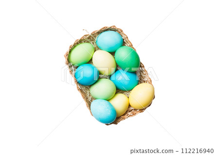 Basket of colorful Easter eggs isolated on white background. Easter basket filled with colored eggs top view holiday concept Basket of colorful Easter eggs isolated on white background. Easter basket filled with colored eggs top view holiday concept 112216940