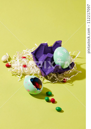 Make your own cute eggs filled with chocolate to give to loved ones on Easter. On green background, paper cut into shreds with blister and Easter eggs decorated 112217097