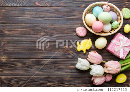 Easter frame with eggs, gift box and tulip on a colored background. The minimal concept. Top view Happy Easter composition. Card with a copy space of the place for the text 112217313
