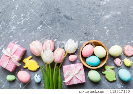Easter frame with eggs, gift box and tulip on a colored background. The minimal concept. Top view Happy Easter composition. Card with a copy space of the place for the text 112217330