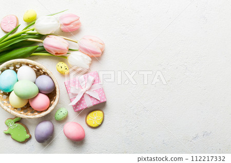 Easter frame with eggs, gift box and tulip on a colored background. The minimal concept. Top view Happy Easter composition. Card with a copy space of the place for the text Easter frame with eggs, gift box and tulip on a colored background. The minimal concept. Top view Happy Easter composition. Card with a copy space of the place for the text 112217332