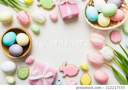 Easter frame with eggs, gift box and tulip on a colored background. The minimal concept. Top view Happy Easter composition. Card with a copy space of the place for the text Easter frame with eggs, gift box and tulip on a colored background. The minimal concept. Top view Happy Easter composition. Card with a copy space of the place for the text 112217335