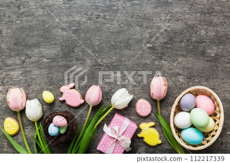 Easter frame with eggs, gift box and tulip on a colored background. The minimal concept. Top view Happy Easter composition. Card with a copy space of the place for the text 112217339