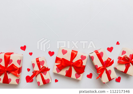 Top view photo of valentine day decorations gift box with red ribbon bow on colored background. Holiday gift boxes with top view 112217346
