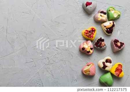 chocolate sweets in the form of a heart with fruits and nuts on a colored background. top view with space for text, holiday concept 112217375