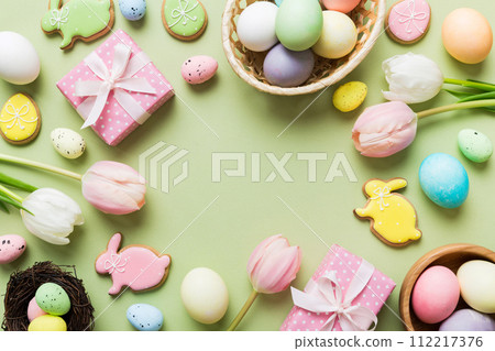 Easter frame with eggs, gift box and tulip on a colored background. The minimal concept. Top view Happy Easter composition. Card with a copy space of the place for the text Easter frame with eggs, gift box and tulip on a colored background. The minimal concept. Top view Happy Easter composition. Card with a copy space of the place for the text 112217376