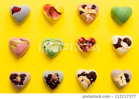 chocolate sweets in the form of a heart with fruits and nuts on a colored background. top view with space for text, holiday concept 112217377