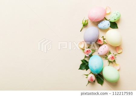 Happy Easter. Easter eggs on colored table with yellow roses. Natural dyed colorful eggs background top view with copy space Happy Easter. Easter eggs on colored table with yellow roses. Natural dyed colorful eggs background top view with copy space 112217593
