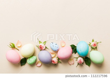 Happy Easter. Easter eggs on colored table with yellow roses. Natural dyed colorful eggs background top view with copy space 112217596