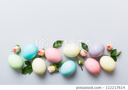 Happy Easter. Easter eggs on colored table with yellow roses. Natural dyed colorful eggs background top view with copy space 112217614