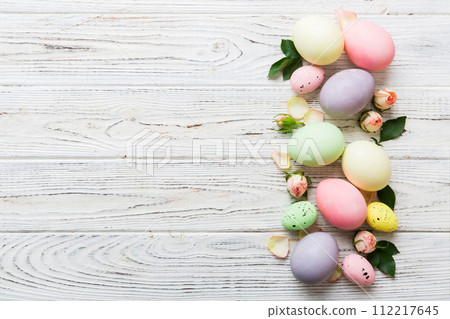 Happy Easter. Easter eggs on colored table with yellow roses. Natural dyed colorful eggs background top view with copy space 112217645