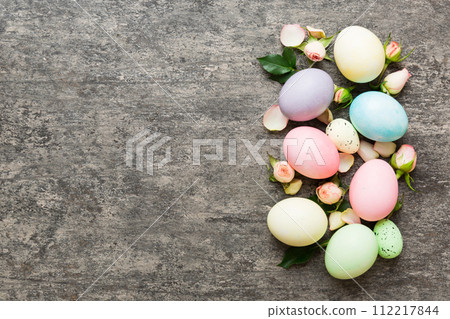 Happy Easter. Easter eggs on colored table with yellow roses. Natural dyed colorful eggs background top view with copy space 112217844