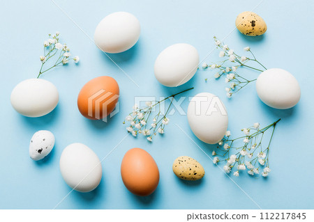 Happy Easter composition. Easter eggs on colored table with gypsophila. Natural dyed colorful eggs background top view with copy space 112217845