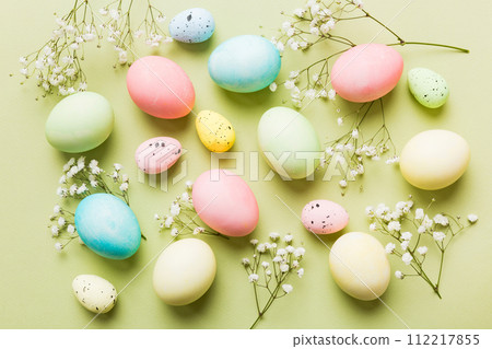 Happy Easter composition. Easter eggs on colored table with gypsophila. Natural dyed colorful eggs background top view with copy space 112217855
