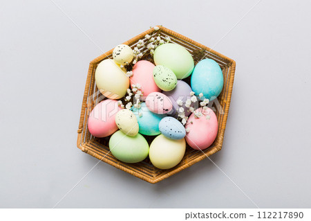 Happy Easter composition. Easter eggs in basket on colored table with gypsophila. Natural dyed colorful eggs background top view with copy space Happy Easter composition. Easter eggs in basket on colored table with gypsophila. Natural dyed colorful eggs background top view with copy space 112217890